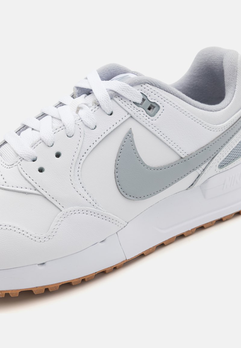 Sneaker bianca in pelle con dettagli grigi, caratterizzata da una suola intermedia texturizzata e lacci rotondi. La suola esterna presenta un design in gomma naturale per una migliore trazione.