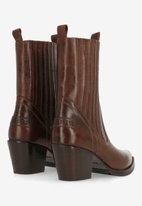 Botas de tobillo de cuero marrón con paneles elásticos acanalados, punta redondeada y tacón grueso. Presenta un detalle de logo en la parte posterior.