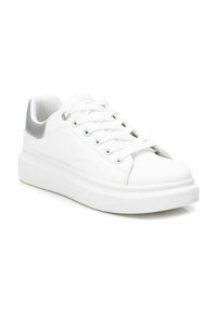 Zapatilla blanca con un exterior de cuero liso, puntera redondeada y un acento plateado en el talón. Presenta cordones planos y una gruesa suela blanca.
