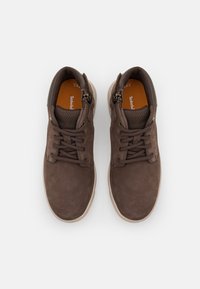 Hnědé kožené boty s texturovaným svrškem, šněrovacím designem, polstrovaným límcem a světlou gumovou podrážkou. Obsahují boční zipy pro snadné obouvání.