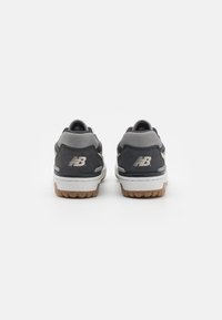 Ein Paar graue und schwarze New Balance Turnschuhe von hinten betrachtet, mit dem Logo auf der Ferse und weißen Sohlen mit braunem Profil.