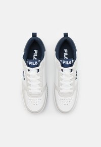 Sneakers bianchi in pelle con accenti blu navy, caratterizzati da un design con lacci, punta forata e logo Fila sulla linguetta e sul lato.