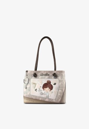 Beigefarbene Handtasche mit braunen Griffen, Fronttasche mit einer Illustration eines Mädchens und dem Text "Verliebt in Wissen" mit dekorativen Anhängern.