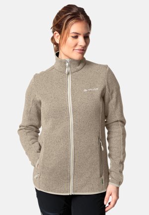 Fleece jacket in beige with a high collar, full front zipper, two side pockets, and contrasting white stitching along the seams.