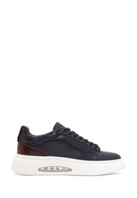 Sneaker in pelle blu navale con una suola bianca, punta tonda, accenti marroni e un cuscinetto d'aria trasparente. Presenta chiusura con lacci e dettagli cuciti.
