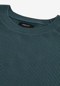 Pull en tricot teal avec un col rond et un tissu texturé. Il présente une étiquette indiquant « NEXT » au niveau du col.