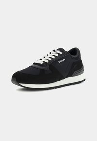 Sneaker sportivo nero realizzato in materiali di rete e suede, con lacci bianchi, logo sul lato e una suola intermedia bianca. Presenta una punta tonda e una suola testurizzata.