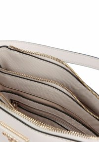 Borsa beige chiaro con cerniera, interno con molteplici scomparti, tessuto testurizzato, accessori in oro e rifiniture nere a contrasto.