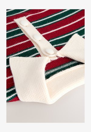 Rdeč-zelen pulover s črtami, pleten s kremasto ovratnico in gumbno lečko. Gumbi so teksturirani in ujemajo z materialom ovratnice.