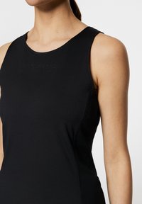 Svart ärmlös topp med rund halsringning, slät yta och diskret präglad logotyp. Designad för en tight passform med minimala sömmar.