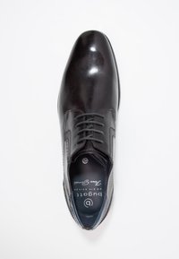 Chaussure habillée en cuir noir avec une finition lisse et brillante. Caractérisée par des lacets, un bout arrondi et des coutures décoratives sur les côtés.