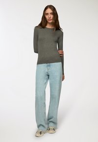 Szary top z długim rękawem w połączeniu z jasnoniebieskimi spodniami typu wide-leg. Całość charakteryzuje się prostym, dopasowanym krojem oraz teksturowanym materiałem. W zestawie wygodne obuwie.