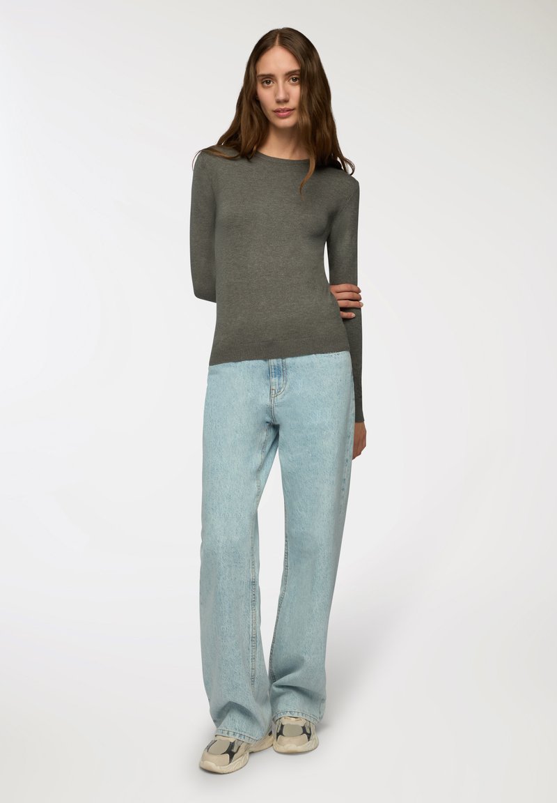 Szary top z długim rękawem w połączeniu z jasnoniebieskimi spodniami typu wide-leg. Całość charakteryzuje się prostym, dopasowanym krojem oraz teksturowanym materiałem. W zestawie wygodne obuwie.