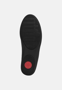 Schwarze Schuhsohle mit strukturiertem Griff, ausgestattet mit erhabenem Logo und einem roten kreisförmigen Akzent, der mit "Comfort Technology" beschriftet ist. Glatte, abgerundete Kanten.