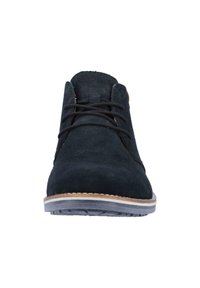 Zapato de ante negro con cordones, punta redondeada y suela marrón clara. Presenta una costura mínima y una textura de superficie suave.