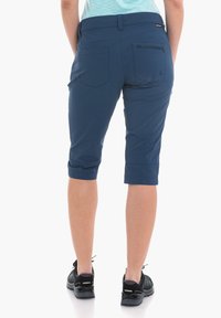 Bermudas azul marino hasta la rodilla, hechas de tela ligera, con bolsillos laterales y traseros. Los puños enrollados añaden un aspecto relajado.