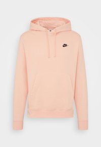 Nike hoodie i ljusrosa, med en framficka, snodd i huvan och en svart logotyp på bröstet. Mjuk bomullsblandning.