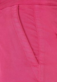 Rosa tyg med en slät textur. Har en sidoficka med rena sömmar och en strömlinjeformad design som framhäver sin avsmalnande form.