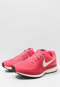 Scarpe da corsa in rete rosa con il logo Nike bianco, tomaia testurizzata, suola ammortizzata e lacci a contrasto. Punta arrotondata e suola piatta in gomma.