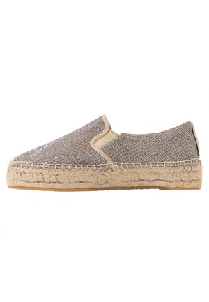 Izceļošanās espadrilles ar tekstūru gaiši brūnā krāsā, ar austu augšējo daļu, bēšiem akcentiem un jūtu virvi kā zoli. Plakana un apaļa pirkstu forma.