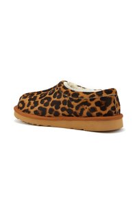 Scarpe slip-on con stampa leopardata, superiore in morbido pelo marrone, suola intermedia beige e suola in gomma. Presentano una punta rotonda e dettagli elastici sui lati.