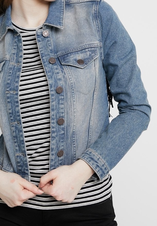 Ljusblå denimjacka med två bröstfickor, metalldrivna knappar och en figurnära design. Under jackan en svart- och vitrandig skjorta.