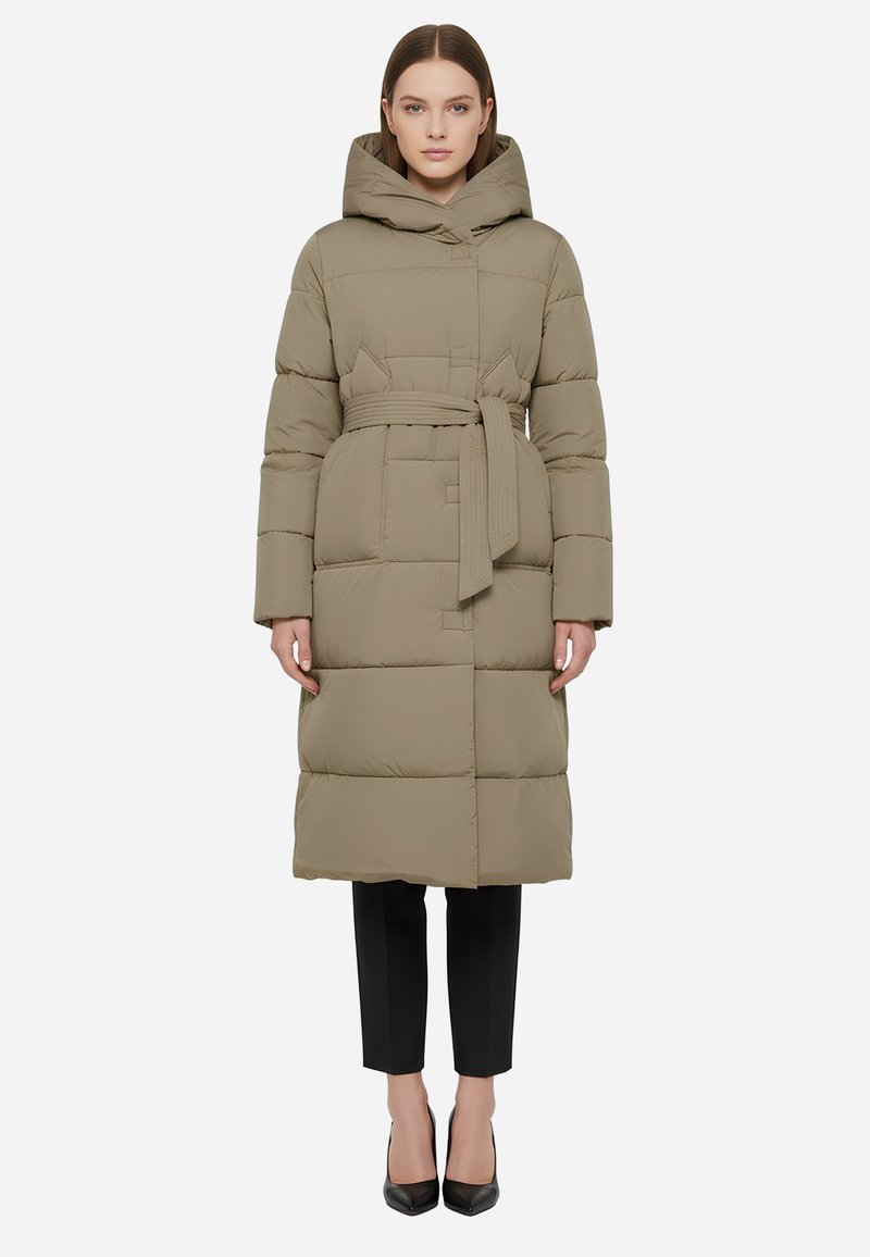 Piumino color marrone chiaro con cappuccio, vita stretta da una cintura e design trapuntato. Maniche lunghe e lunghezza fino al ginocchio, abbinato a pantaloni neri e tacchi.