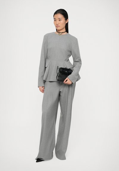 Szürke csíkos kosztüm peplum sziluettel; széles lábú nadrág. Fekete textúrált kézitáska, struktúrált kialakítással. Egyszerű choker nyaklánc.