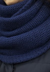 Marine gebreide infinity-sjaal met een gestructureerd stekenpatroon, met een zachte feel en een nauwsluitende pasvorm rond de nek.