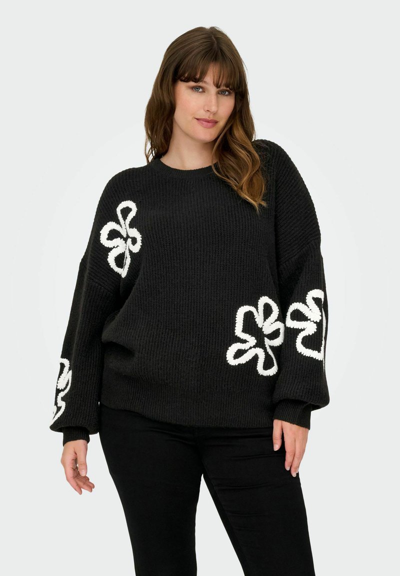 Zwarte gebreide trui met witte bloemenborduursels op de mouwen. Heeft een losse pasvorm, ronde halslijn en een textuurstof.