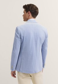 Hellblauer Blazer aus einem weich strukturierten Stoff, mit einem Reverskragen, einer Zwei-Knopf-Verschluss und Doppelschlitzen. Akzentuiert mit goldenen Knöpfen.