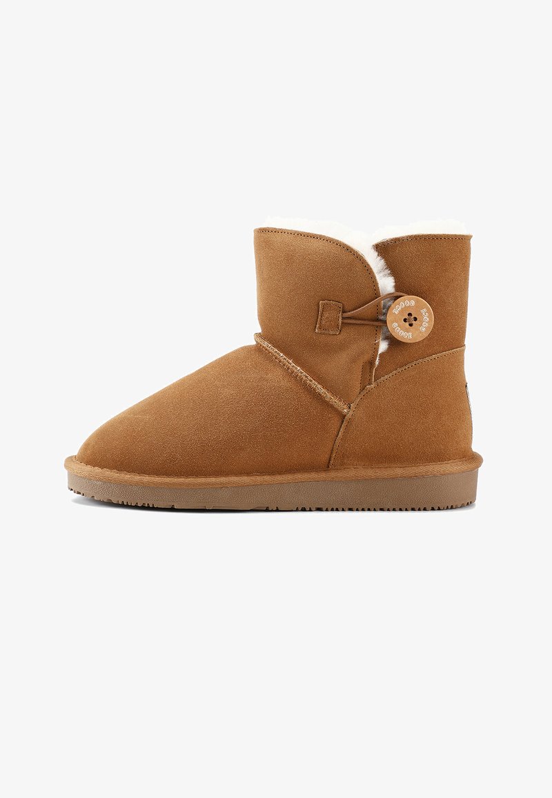 Botas de ante marrón claro hasta el tobillo con puntera redonda, forro suave de piel de animal, diseño de envoltura diagonal y cierre decorativo con botón de madera. Suela de goma plana.