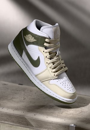 Korkeavartiset Air Jordan -tennarit valkoisina, beigenä ja oliivin vihreänä, nauhoilla, Nike swooshilla ja Air Jordan siipilogoilla.