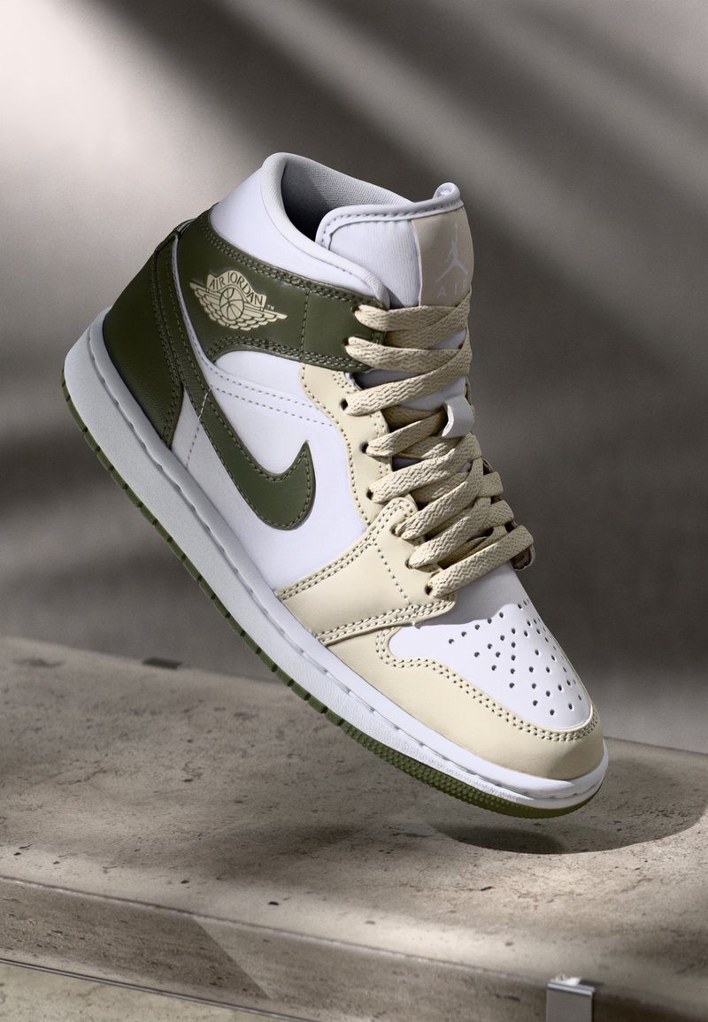 Basket montante Air Jordan en blanc, beige et vert olive avec lacets, logo Nike swoosh et logo ailes Air Jordan.