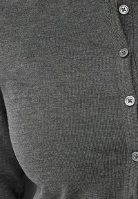 Grå cardigan i ribbad tyg, med v-ringning, knappstängning fram och runda plastknappar. Slät textur med figurnära passform.