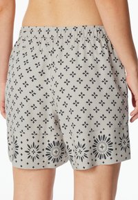 Shorts gris à motif avec une taille élastique, arborant un design géométrique et des accents floraux noirs contrastants à l'ourlet.
