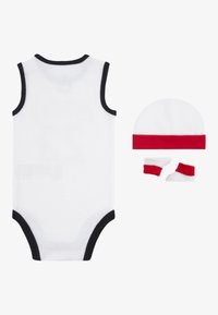 Hvit bomulls baby body med svart trim, akkompagnert av en hvit hatt med rød stripe og matchende røde sko.