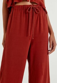 Roestkleurige, lichtgewicht, loszittende broek van een zachte stof, met een elastische tailleband en een gestrikt koorddetail.