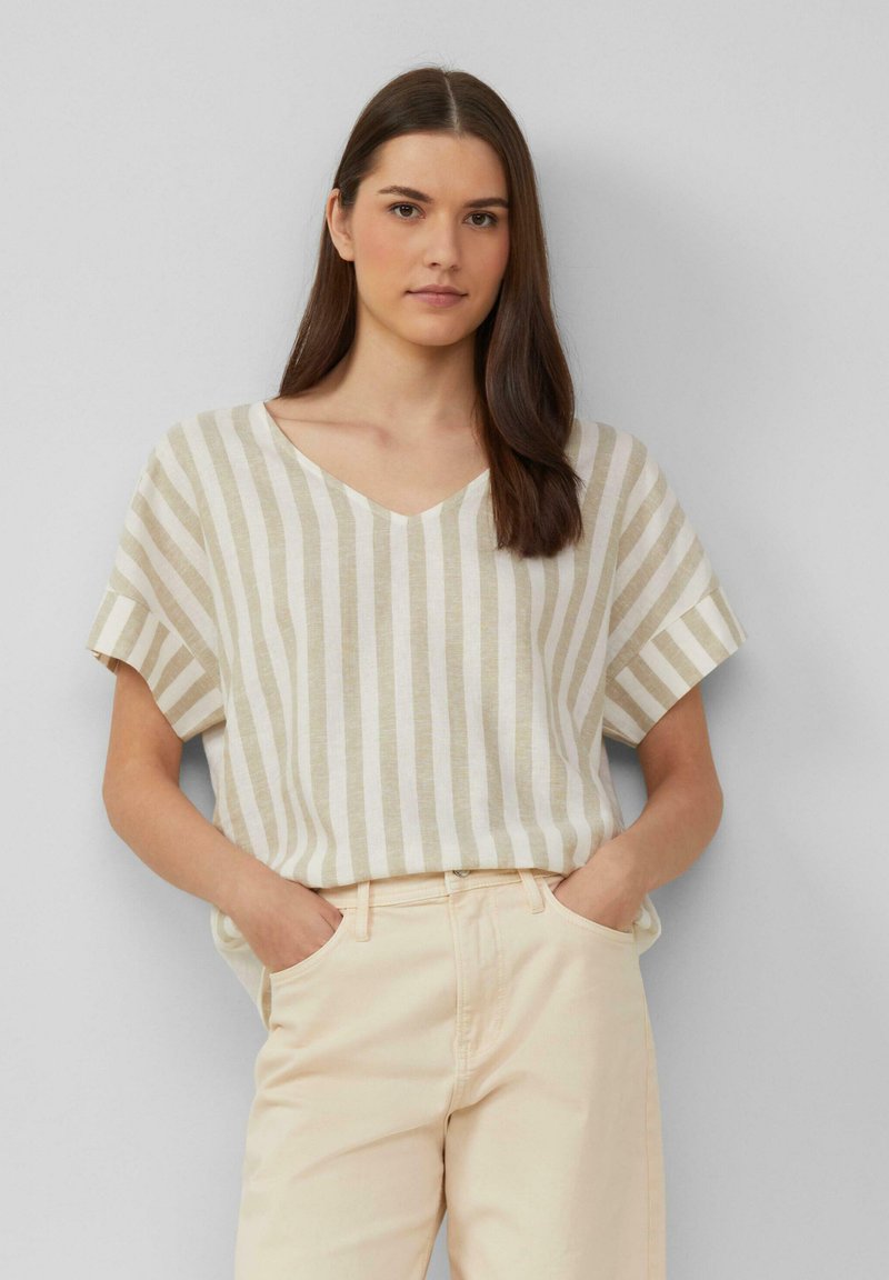 Beige en crèmekleurige gestreepte blouse met een V-hals en korte mouwen, gemaakt van lichtgewicht stof. Gecombineerd met lichte broek.