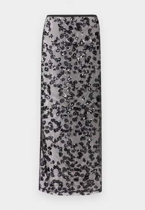 Dlhá čierna sukňa s priehľadnou vrstvou zdobenou rozptýlenými čiernymi flitrovanými kvetinovými vzormi na neutrálnom pozadí.