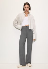 Szare spodnie o szerokich nogawkach o gładkiej teksturze, zestawione z krótką, w paski koszulą zapinaną na guziki oraz białym topem na ramiączkach. Akcentowane sneakersami.