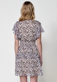 Leopardenmuster Kleid mit schwingenden Ärmeln, gerafftem Bund und geschichtetem Rüschensaum. Transparenter Stoff in hellbeigen und braunen Tönen. Rückansicht.