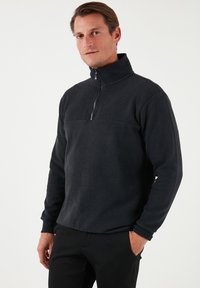 Pullover con mezza zip in pile blu scuro, caratterizzato da una trama uniforme, maniche lunghe e colletto. Design minimalista senza motivi visibili.