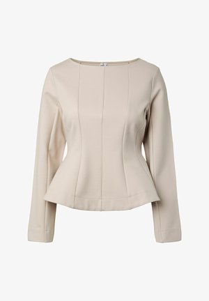 Blouse beige à manches longues pour femme avec un col rond et une taille ajustée légèrement évasée, sur un fond uni.