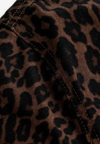 Leopardenmusterstoff in Braun und Schwarz mit einer strukturierten Oberfläche, auf der sich kräftige schwarze Flecken vor einem reichen braunen Hintergrund abheben.