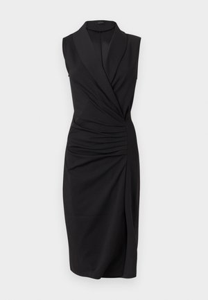 Robe noire sans manches longueur genou avec devant croisé, détail froncé sur le côté, et col à revers large.