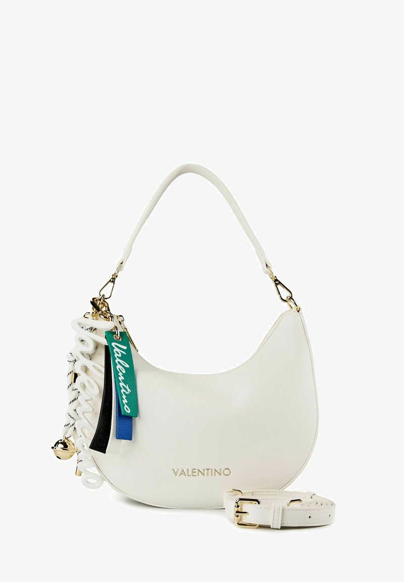 Sac bandoulière croissant blanc Valentino avec ferrures dorées, bandoulière amovible et étiquettes de marque colorées suspendues sur le côté.