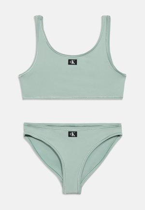 Set de bikini verde mentă cu top cu decolteu rotund și chiloți asortați, ambele având o etichetă mică neagră cu logo-ul Calvin Klein.