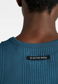 Blaues geripptes Tanktop mit einem schwarzen G-Star RAW Etikett hinten. Der Stoff hat ein strukturiertes Aussehen und ein figurbetontes Design.