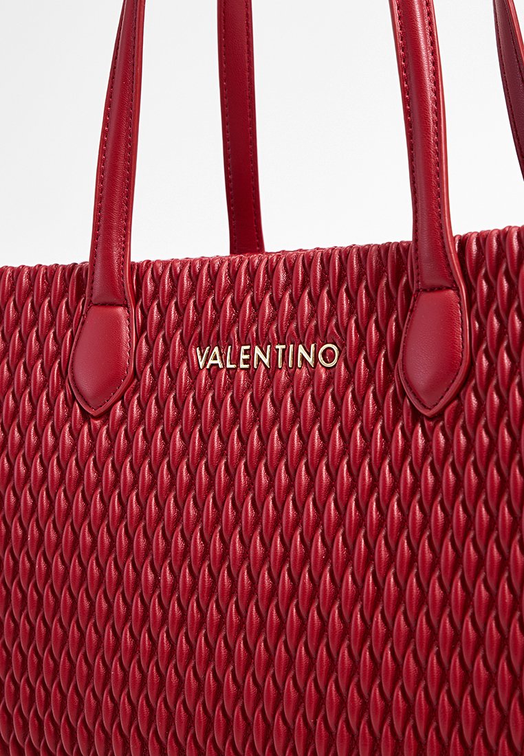 Sac en cuir rouge avec un design tissé texturé, doté de poignées lisses et d'un accent doré avec le logo "VALENTINO" sur le devant.